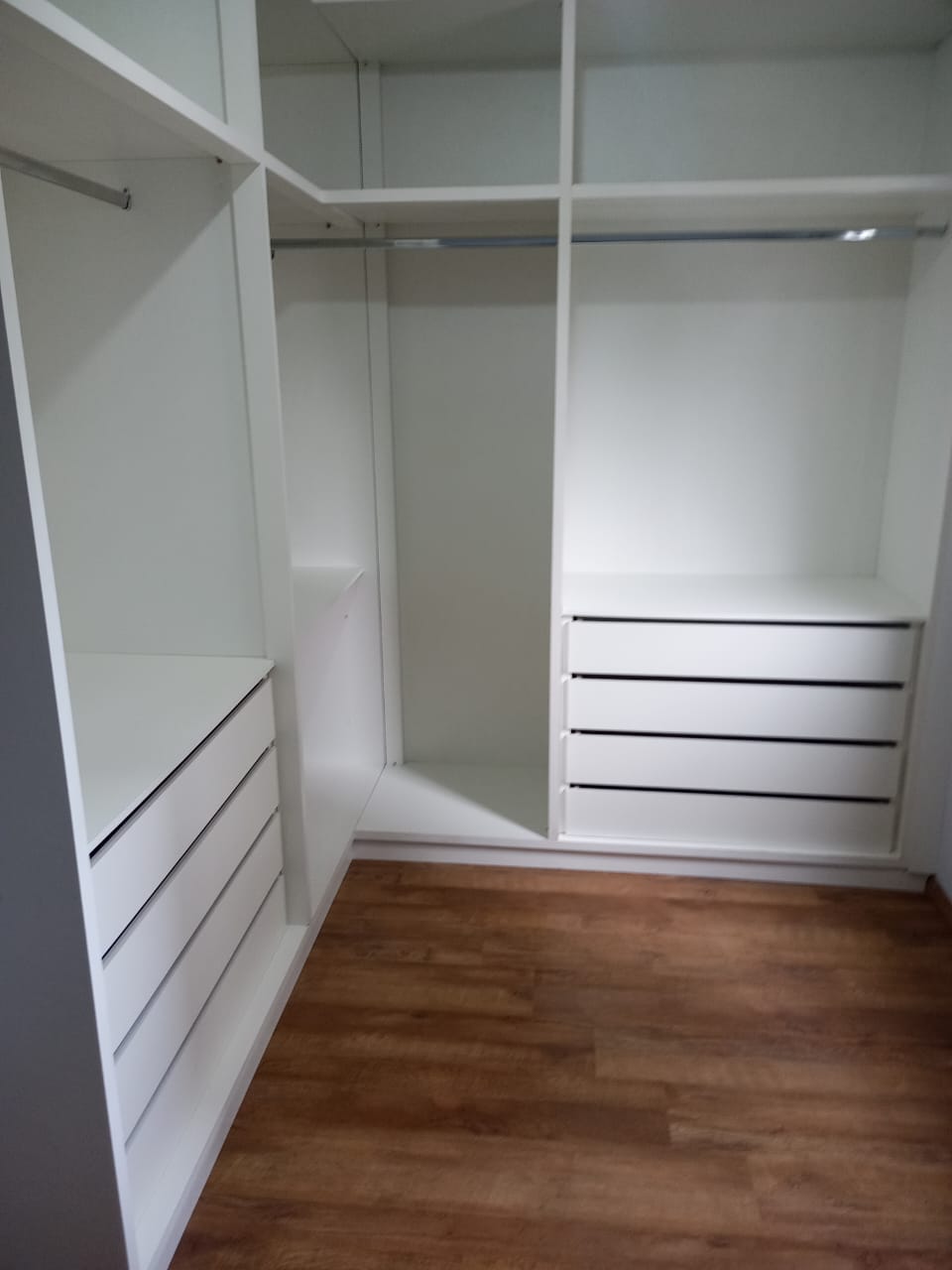 Closet sob medida em MDF branco com gaveteiros, prateleiras e varão para cabides.
