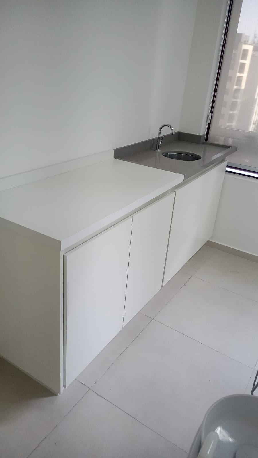 Bancada de cozinha sob medida em MDF branco com cuba de inox instalada.