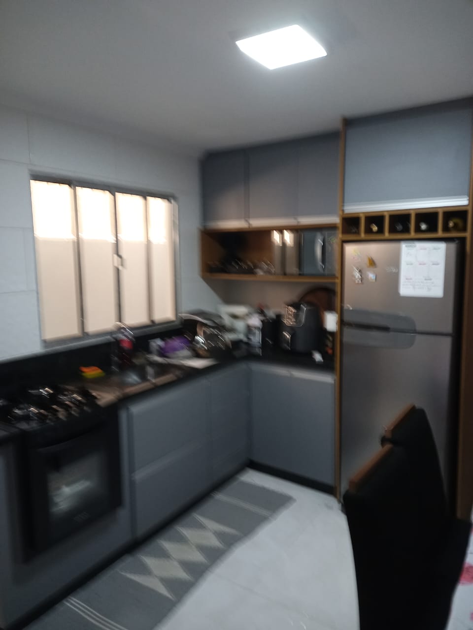 Cozinha planejada sob medida com armários em MDF cinza, nicho para adega e integração com eletrodomésticos.